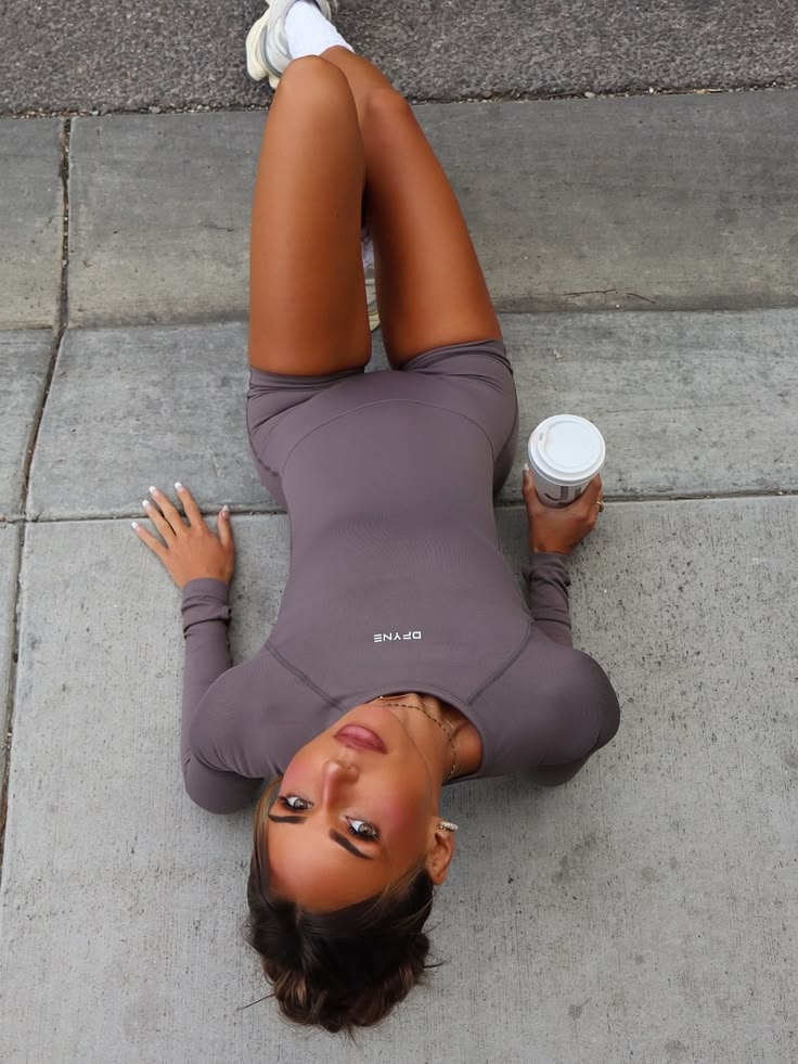 Overhead frame of a model lying on pavement in a one-piece